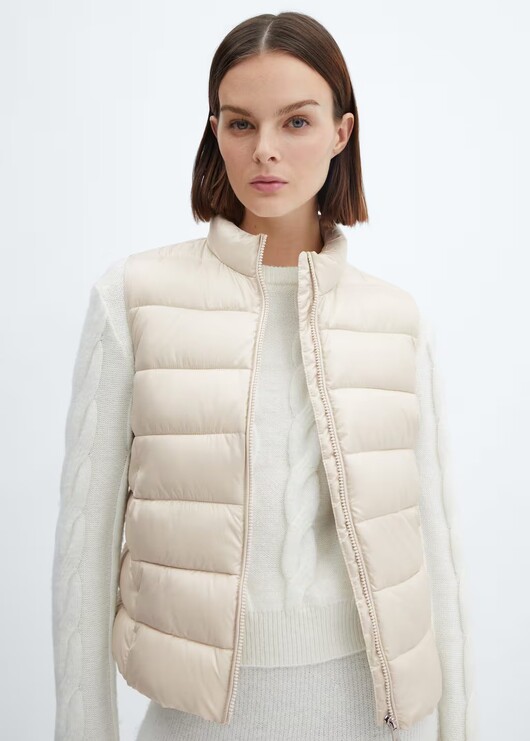 Ivory puffer gilet by Mango worn over white sweater.